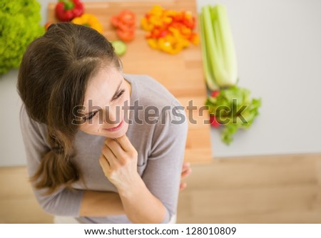Portrait of thoughtful young woman in kitchen Royalty-Free Stock Photo #128010809