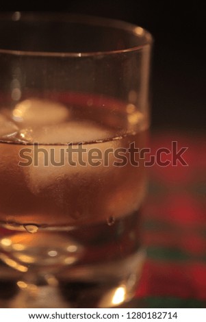 alcoholic beverage - vertical photography of a transparent whiskey glass with liquid and ice cubes, on a white table cloth