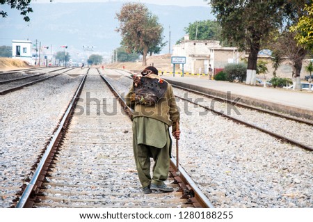 A railroad technician walking on the track with old rustic leather tools bag 