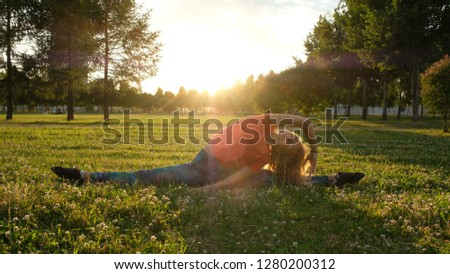 Gymnast woman sits on the longitudinal and transverse splits. Stretching in the city park