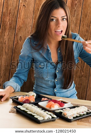 Portrait Of A Young Woman Eating Sushi Maki against a wooden background