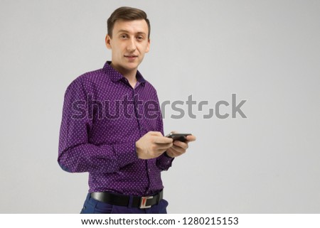 young man with mobile phone in his hands is isolated on light background