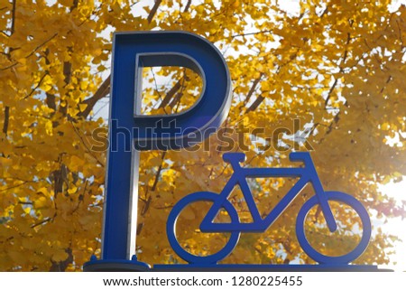A display of contrast color between the blue bicycle parking sign with a vivid yellow Gingko leaves in background