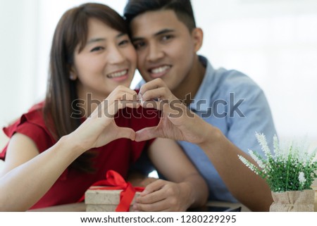 Asian lovers couple doing love sign with hand together