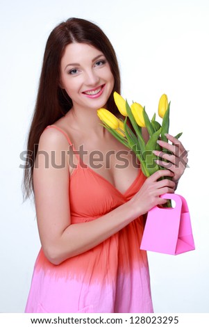 Studio image of gorgeous young woman with yellow tulips/Beautiful girl holding a bouquet of fresh flowers on Holiday
