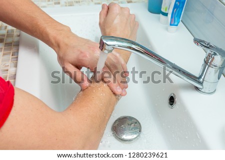 A man washes his hands up to the elbows under the tap Royalty-Free Stock Photo #1280239621