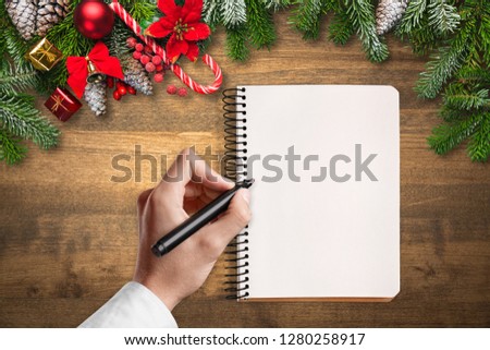 Flat lay christmas clipboard mockup. Woman's hands holds black brush pen. Blank white paper sheet clip board mock up. Winter holidays mood for hand lettering. Merry christmas happy new year. Flatlay