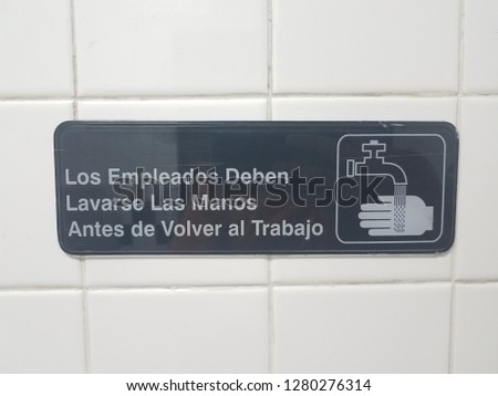 employees should wash their hands before returning to work sign in Spanish