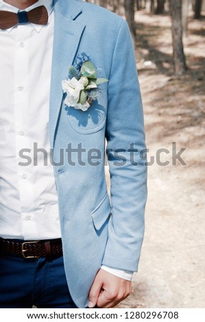 Groom in a suit with a bow tie and a boutonniere. Flower design, floristry. Wedding day and accessories