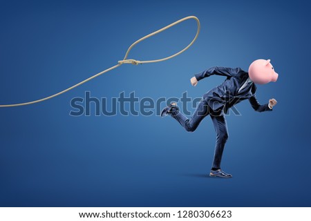 Businessman with a piggy bank head running from a loop on the blue background. Business and finance. Banking and financial industry. Management. Savings. Royalty-Free Stock Photo #1280306623