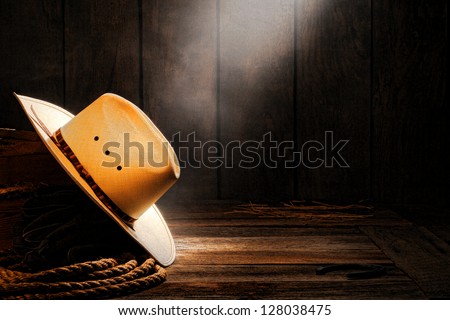 American West rodeo cowboy traditional white straw hat on a wooden box with ranching rope in a smoky and dusty old wood ranch barn lit by soft diffused light