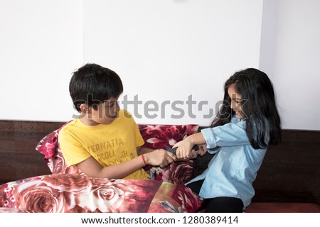 Boy and girl fighting over tv remote control at home Royalty-Free Stock Photo #1280389414