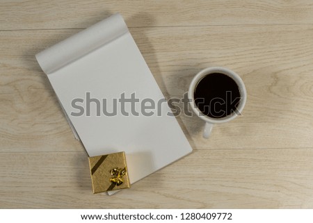Overhead of gift box, notepad and black coffee on wooden table