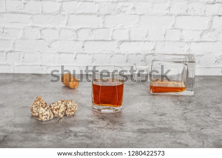 A glass of brandy or whiskey on a background of gray stone with truffles. Place for text