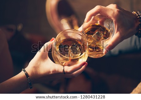 A couple makes a toast with two glasses of whiskey Royalty-Free Stock Photo #1280431228