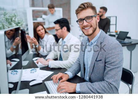 smiling businessman uses a computer to analyze financial data