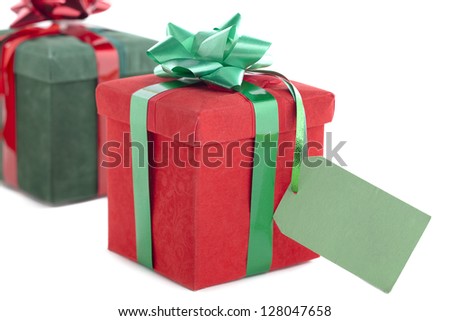 Closeup shot of red Christmas present with empty placard with green gift box in background.