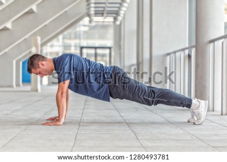 Picture of a young athletic man doing push ups in a sports center, preparing for morning workout. 
