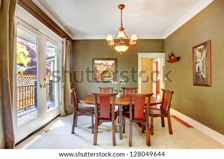 Green classic dining room with art and large door.