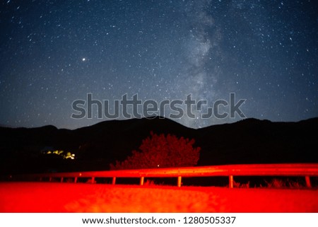 
starry sky in the mountains of Georgia. Road in the red light of auto lamps.