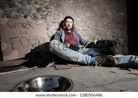 Man in dirty rags hugging dog sitting on sidewalk