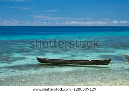 Melanesia, Solomon Islands, Santa Cruz Island group, Malo Island. Clear shallow bay and coral reef, typical wooden canoe. Snorkeler in the distance. Royalty-Free Stock Photo #1280509129