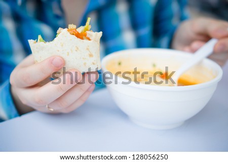 Roll with chicken and vegetables and plate of soup with noodles in fast food restaurant