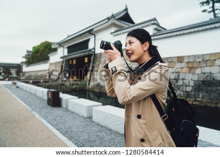 Female photographer taking pictures of beautiful blue sky standing outside japanese nijo castle kyoto japan. young girl self guided travel trip in asia. woman lens man holding camera zooming up.