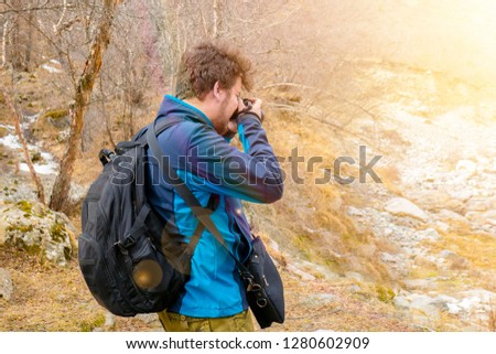 Nature trekker photographer with backpack taking a picture in mountains forest