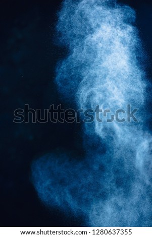Flour powder explosion in motion. Action food photography. Light blue dust on a black background with copy space