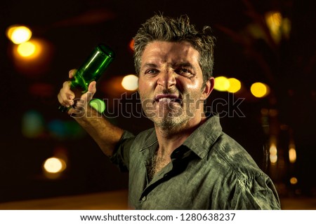 young upset and aggressive drunk man in pub at night holding beer bottle threatening ready to fight as the violent thug troublemaker in every bar and alcohol addict furious guy Royalty-Free Stock Photo #1280638237