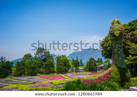 a peacock big statue made from green grass and plant with flower garden park as background - photo indonesia Royalty-Free Stock Photo #1280665984