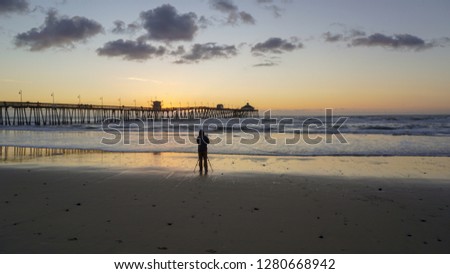 Photographer setting up to shoot the sunset over Imperial Beach pier, pacific ocean, California
