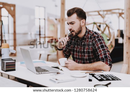 Laptop Screen. Cup of Coffee. Desk. Workplace. Mobile Phone. Young Male. Businessman. Creative Worker. Creates Ideas. Project. Sit. Brainstorm. Work. Office. Creative Worker. Inspiration. Eyeglasses. Royalty-Free Stock Photo #1280758624
