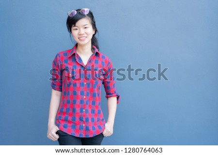 Attractive young asian woman wearing fashionable clothes and Sunglasses on hair posing on blue navy wall background with copy space text.
A portrait of a beautiful asian woman smiling at camera.