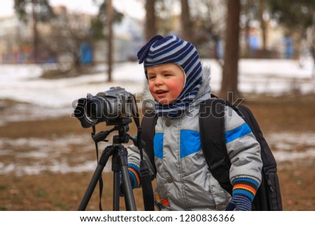 Little boy taking pictures in winter park