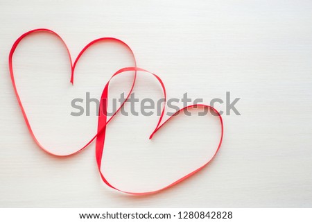 Valentines Day background with two red ribbon shaped as heart on wood table, copy space for text. Love, wedding concept. Top view, flat lay