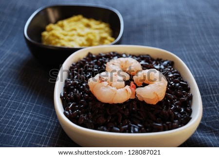 Black rice with shrimp and chickpeas cream in china bowls