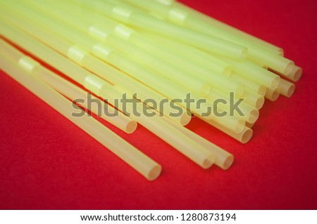 closeup of yellow plastic straw collection on red background