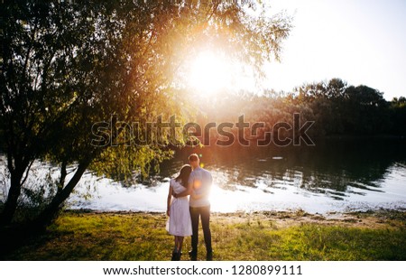 young loving couple are looking at each other tenderly and hugging at sunset near the river, photo to the day of Saint Valentine