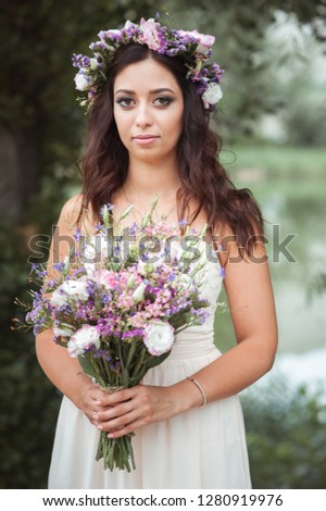 Lovely young bride in a beautiful dress with a bouquet. Happy wedding.