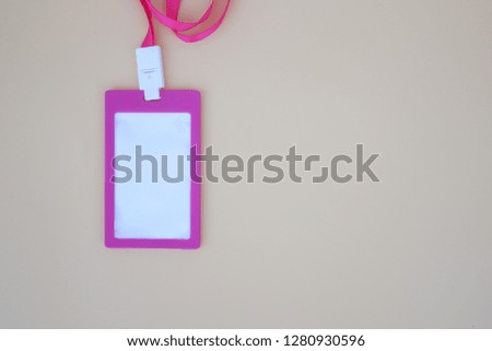 A pink identity name tag necklace on the  brown background. 