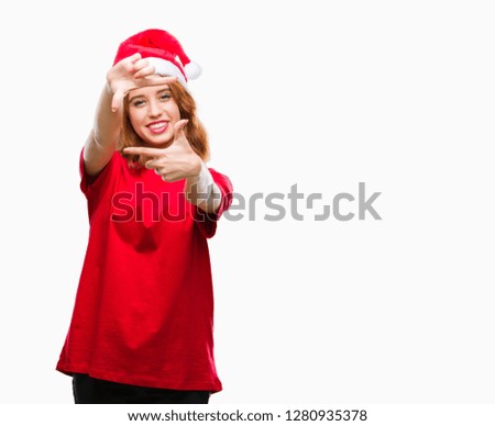 Young beautiful woman over isolated background wearing christmas hat smiling making frame with hands and fingers with happy face. Creativity and photography concept.