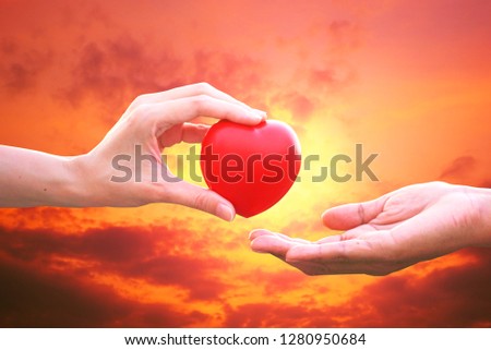 Friend 's hand give red heart to encourage loser with sunset sky background 