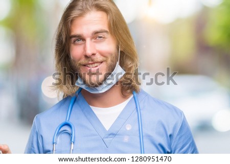 Young handsome doctor man with long hair over isolated background with a big smile on face, pointing with hand and finger to the side looking at the camera.