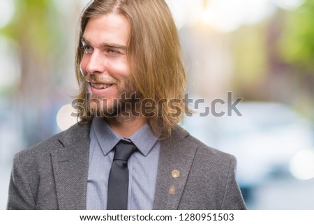 Young handsome business man with long hair over isolated background looking away to side with smile on face, natural expression. Laughing confident.