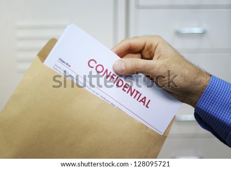 Hand holding envelope with top secret confidential documents Royalty-Free Stock Photo #128095721