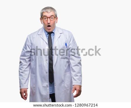Handsome senior doctor, scientist professional man wearing white coat over isolated background afraid and shocked with surprise expression, fear and excited face.
