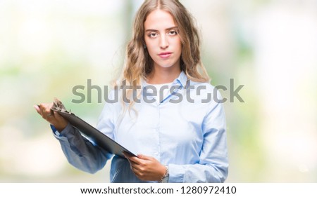Beautiful young blonde business woman holding clipboard over isolated background with a confident expression on smart face thinking serious