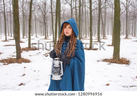 Young woman in retro blue coat walk in the foggy park in the winter times, snow and trees background,fantasy or fairy concept